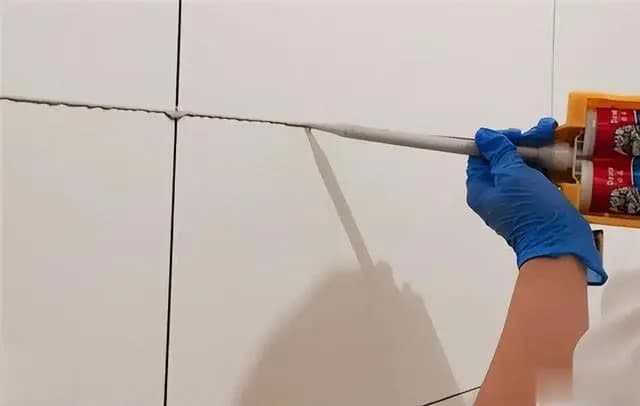 施工人员正在使用刮板清理多余的白水泥,展示填缝剂的施工过程