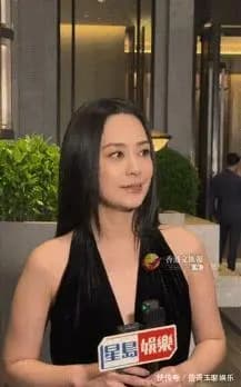 甘比身穿西装大衣手持名牌包